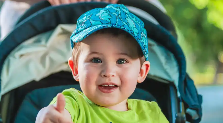 a boy is happy being pushed in a stroller at a park