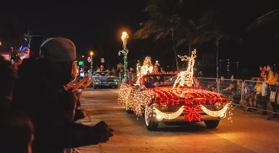 an antique convertible covered in Christmas lights drives along the hollywood broadwalk